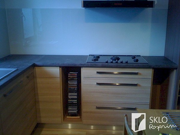Dřevěná kuchyňská linka s tmavou deskou a skleněným obkladem za kuchyňskou linkou